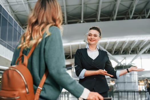 Assistance by woman in formal clothes. Young female tourist is in the airport at daytime.