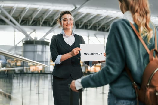 Assistance by woman in formal clothes. Young female tourist is in the airport at daytime.