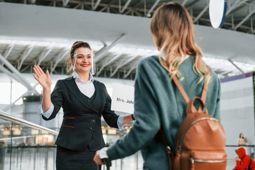 Woman with plate with text. Young female tourist is in the airport at daytime.