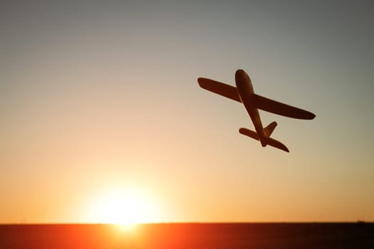 Silhouette of an airplane at sunset. Toy plane against the backdrop of the sunset sky. Vacation and travel concept