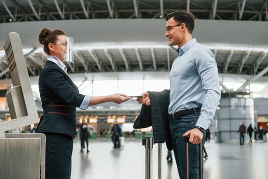 Checking documents. Young businessman in formal clothes is in the airport at daytime.