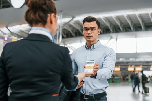 Checking documents. Young businessman in formal clothes is in the airport at daytime.