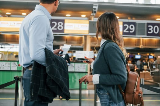 Looking at the employee. Young couple is in the airport together.