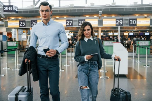 Walking forward. Young couple is in the airport together.