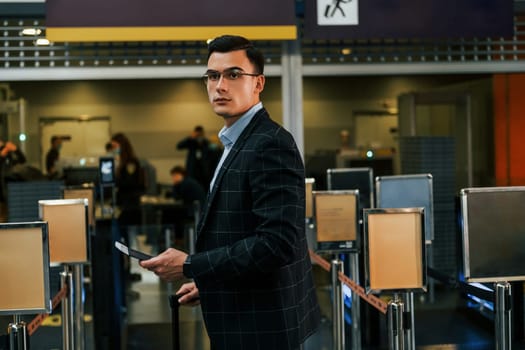 Modern background. Young businessman in formal clothes is in the airport at daytime.