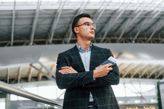 Serious look. Young businessman in formal clothes is in the airport at daytime.