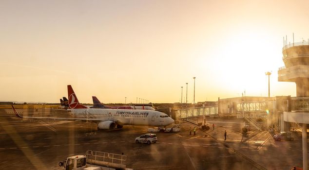 Catania Airport - May, 27: View of the airplanes of Turkish airlines and Wizz air docked in the airport runway at sunset, on the right the control tower on May 27, 2021