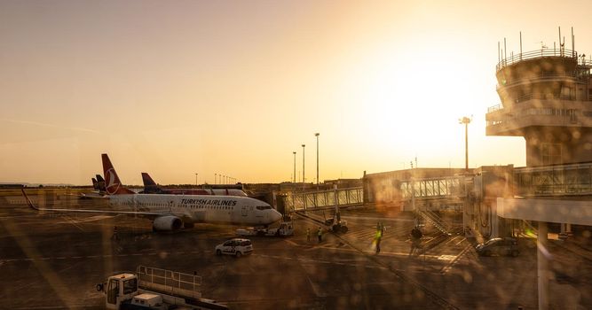 Catania Airport - May, 27: View of the airplanes of Turkish airlines and Wizz air docked in the airport runway at sunset, on the right the control tower on May 27, 2021