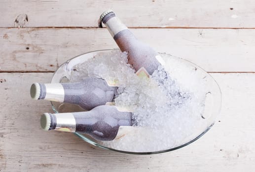 Three frozen glass bottles of beer immersed in the ice