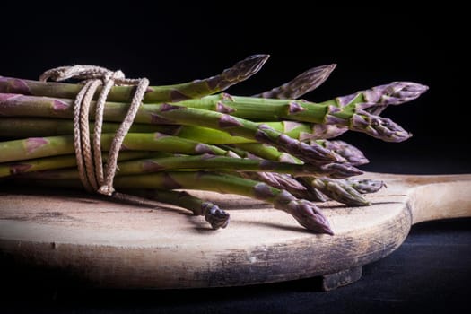Close up of bunch of fresh asparagus on cutting board