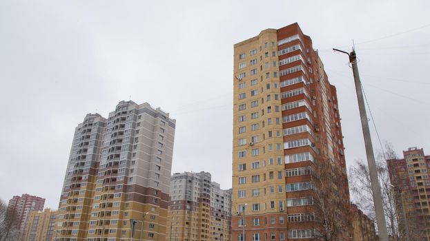 High-rise residential buildings in a new area of the city built of bricks. Against the background of the gray sky. Modern new buildings, building facades. Real estate and urban architecture concept.