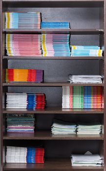 Bookcase with textbooks and notebooks neatly laid out on the shelf. Rack with shelves in the classroom of the school. Teaching and methodological aids for the work of the teacher and students.