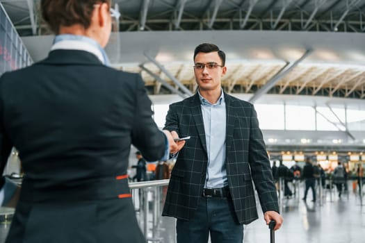 Passing through. Young businessman in formal clothes is in the airport at daytime.