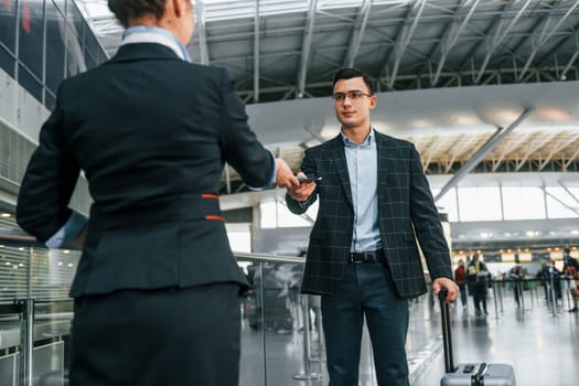 Passing through. Young businessman in formal clothes is in the airport at daytime.