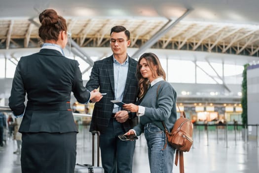 Giving the documents. Young couple is in the airport together.