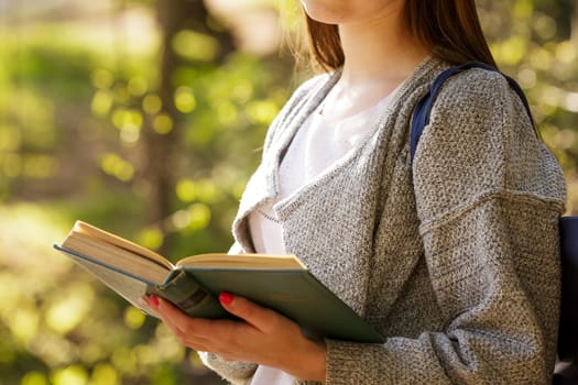 Female portrait of a young Caucasian woman in a park with a book in hand on a sunny day