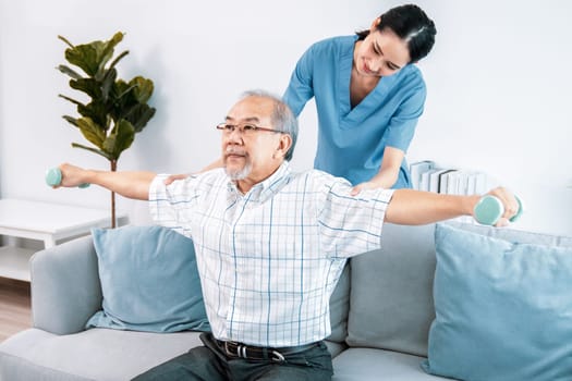 Contented senior patient doing physical therapy with the help of his caregiver. Senior physical therapy, physiotherapy treatment, nursing home for the elderly