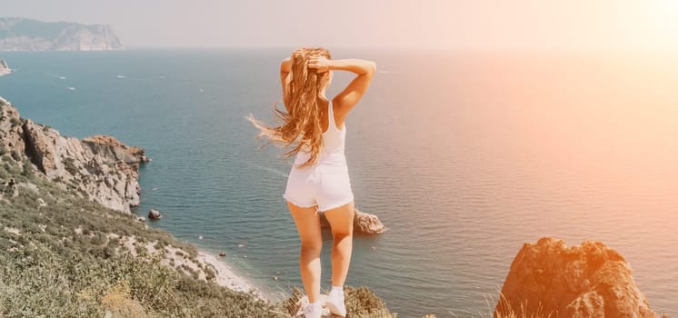 Woman travel sea. Young Happy woman in a long red dress posing on a beach near the sea on background of volcanic rocks, like in Iceland, sharing travel adventure journey