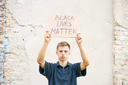 Poster that says black life matters in the hands of a young man. Caucasian guy staged a protest demonstration against racism, wrote a slogan on cardboard