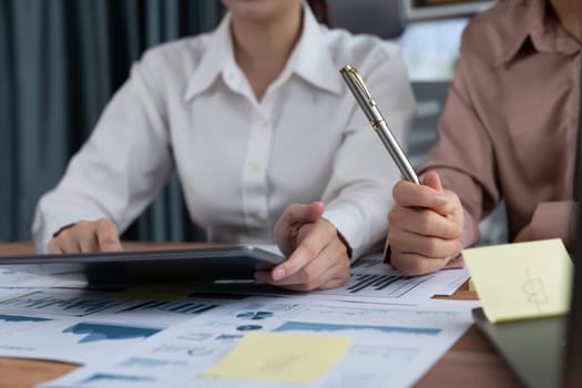 Analyst team colleague discuss financial data on digital dashboard, analyzing charts graph display on laptop and tablet screen. Modern office use business intelligence to plan marketing. Enthusiastic