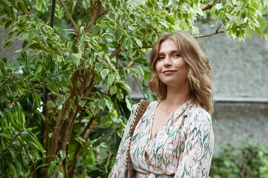 cute young blonde woman posing and smiling among the greenery in the greenhouse