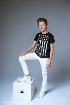 young guy of European appearance posing on a gray background in a black T-shirt, fashionable young man