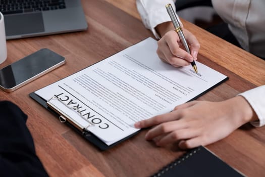 Closeup hand signing contract document with pen, sealing business deal with signature. Businesspeople finalizing business agreement by writing down signature on contract paper. Enthusiastic