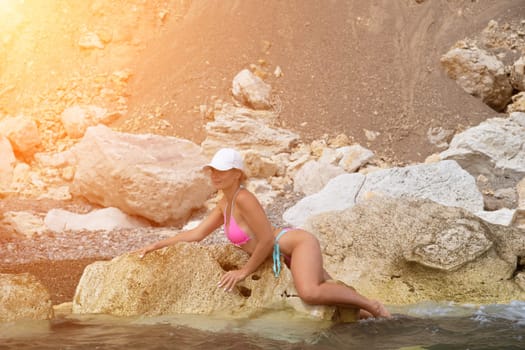 Woman travel sea. Young Happy woman in a long red dress posing on a beach near the sea on background of volcanic rocks, like in Iceland, sharing travel adventure journey