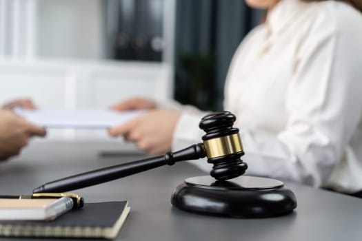 Focus closeup wooden gavel on blur background of lawyer colleagues or drafting legal documents on their workplace at law firm office. Hammer of justice for righteous and equality judgment. Equilibrium