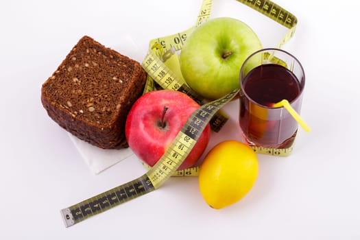 Rye bread with green and red apples and juice in a glass on a white plate with a yellow measuring tape. Diet and healthy food concept