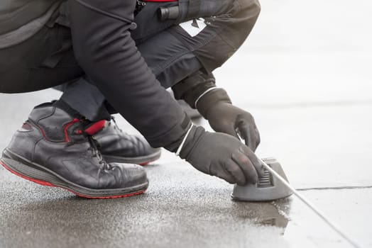 Ground wire. A worker lays a ground cable on the roof of a building. Electrician fixing aluminum wire for grounding solar panels.