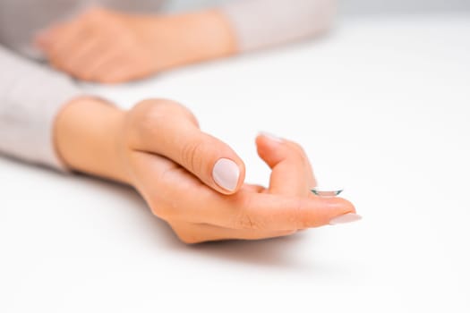Woman hand holding eye contact on the white surface.