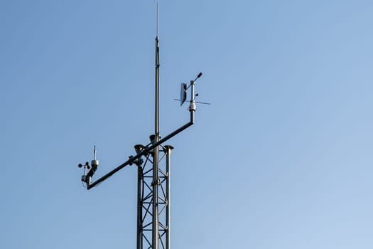 Communication antenna pole stands against clear blue sky. High antenna provides connection among relay cell service stations closeup