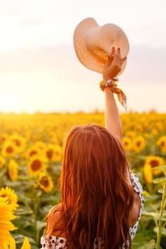 Girl with long hair stands with her back in field of blooming sunflowers in the rays of the setting sun. Beauty in nature. Free young woman enjoying the freshness of the evening
