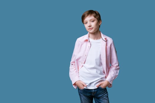 Portrait of a young guy of European appearance in a white T-shirt and a pink shirt posing on a blue background