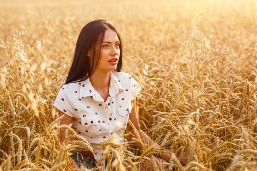 Beauty Girl Outdoors enjoying nature on wheat field. Beautiful Model girl with long hair on golden Field, Sun Light. Glow Sun. Free Happy Woman.