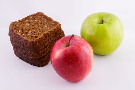 sliced rye bread on a white background with green and red apples