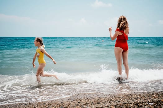 Happy loving family mother and daughter having fun together on the beach. Mum playing with her kid in holiday vacation next to the ocean - Family lifestyle and love concept.