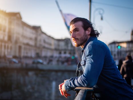 One handsome young man in urban setting in European city, Turin in Italy, standing and looking away