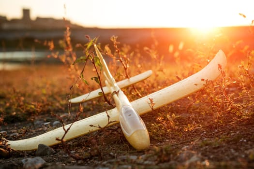 The toy plane lies on the grass at sunset. On a grass field in the russian countryside.