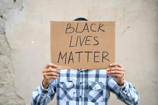 Man holding cardboard with the inscription, black life has value. Caucasian guy with a poster demonstrates his protest, against the background of wall