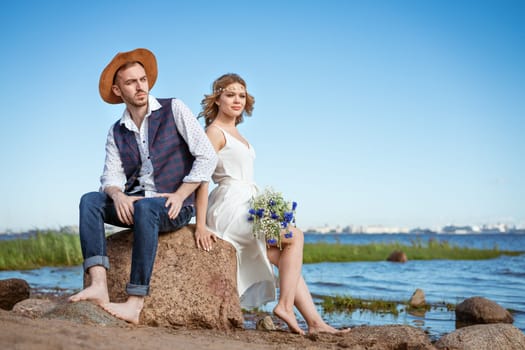 happy caucasian couple man and woman on the beach, summer day holding a bouquet of flowers in her hand