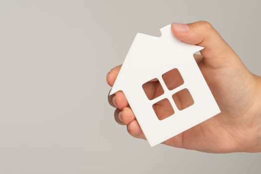 Buying real estate on credit. Model of a white house in hands on a blurred background. Buy a house or apartment, mortgage real estate concept, with copy space.