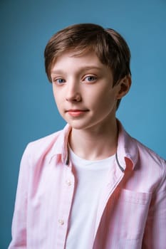 Portrait of a young guy of European appearance in a white T-shirt and a pink shirt posing on a blue background