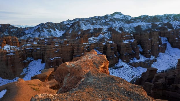 Charyn Grand Canyon with orange rock walls. Aerial view from the drone of the steep canyon walls, cracks and tunnels. There is snow in places. Beautiful sunset and sunrise. Brother of the Grand Canyon