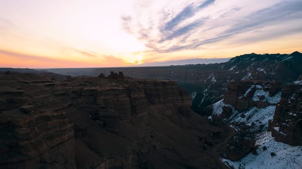 Charyn Grand Canyon with orange rock walls. Aerial view from the drone of the steep canyon walls, cracks and tunnels. There is snow in places. Beautiful sunset and sunrise. Brother of the Grand Canyon