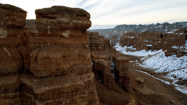 Charyn Grand Canyon with orange rock walls. Aerial view from the drone of the steep canyon walls, cracks and tunnels. There is snow in places. Beautiful sunset and sunrise. Brother of the Grand Canyon