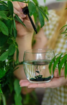 A woman drinks liquid chlorophyll. Selective focus. Nature.