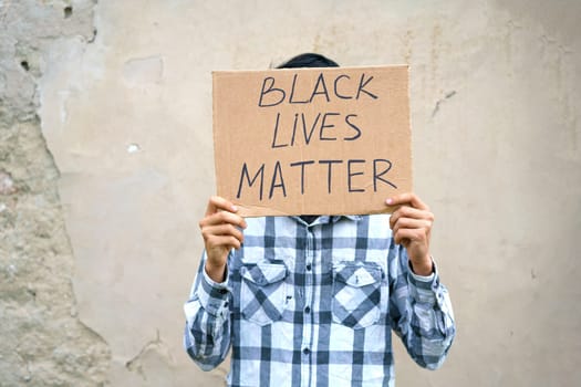 Poster that says black life matters in the hands of a young man. Caucasian guy staged a protest demonstration against racism, wrote a slogan on cardboard