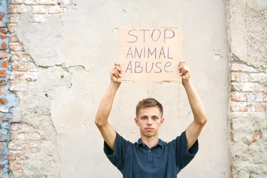 Stop animal abuse guy holding a cardboard box with the inscription. Animal activist. Caucasian young man stands in protest against animal bullying